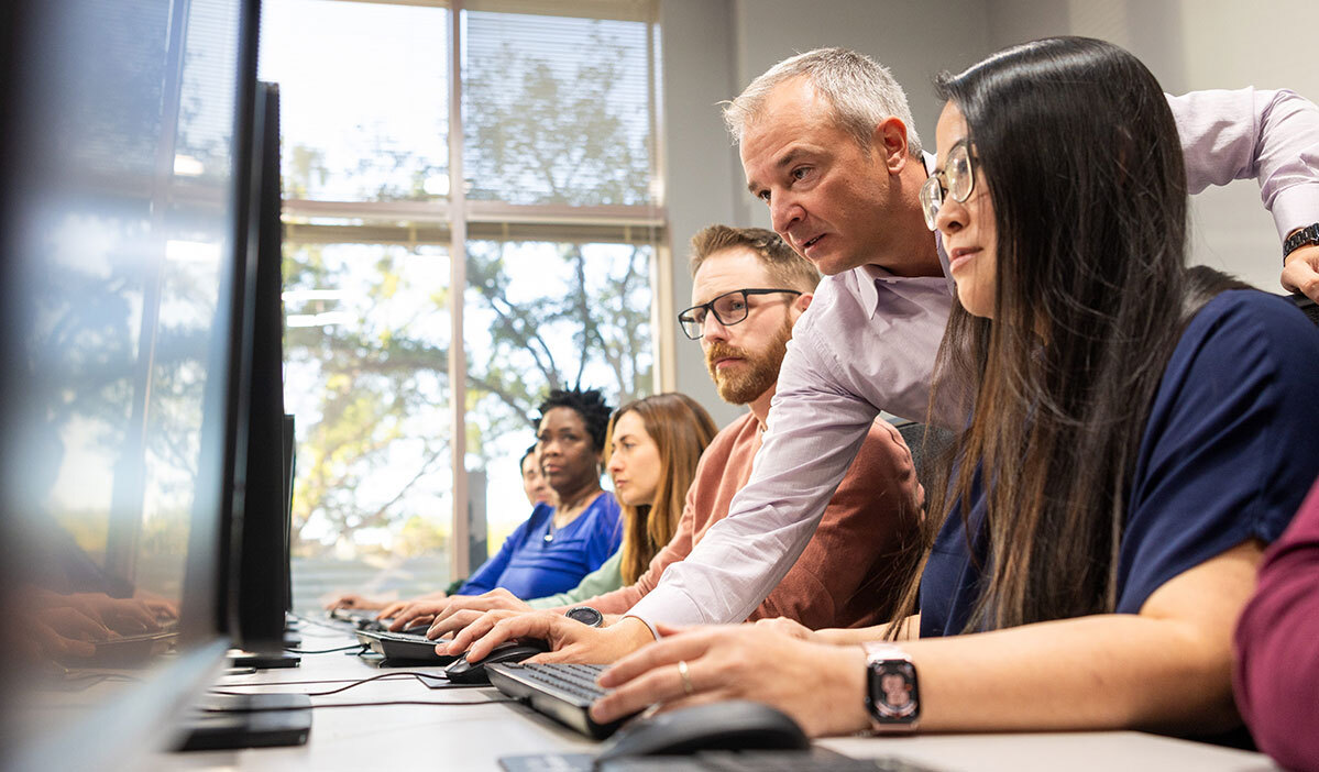 Instructor supporting students at trading desks